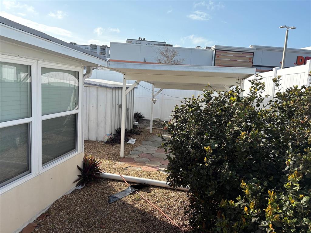 A backyard area features a metal carport, a small storage shed, and a stone patio — 111 174TH AVENUE E, REDINGTON SHORES, FL