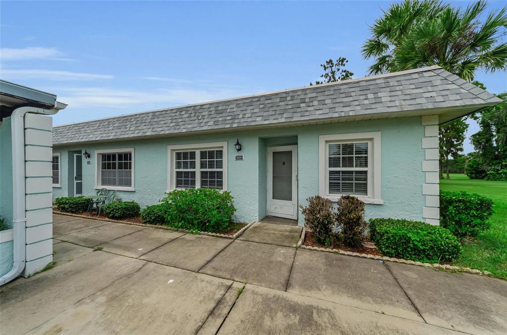A light green, single-story exterior with a gray shingled roof and a concrete walkway — 3684 TROPHY BOULEVARD, NEW PORT RICHEY, FL