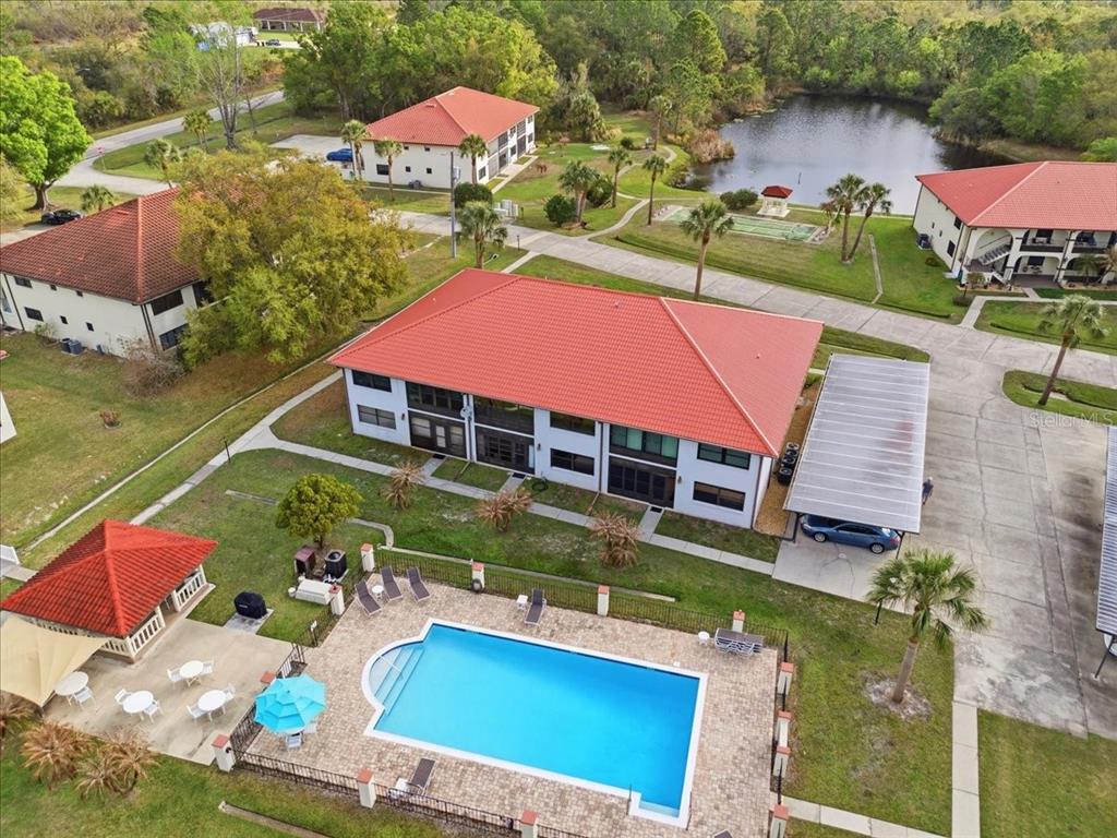 An aerial view shows a multi-story building with a red roof, pool, and carport — 2903 GRANADA COURT UNIT 2903, LAKE WALES, FL