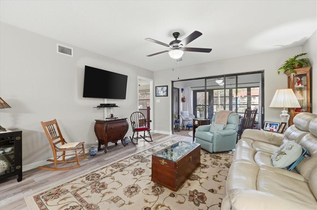A living room features a light-colored sofa, a wooden coffee table, and a ceiling fan — 2903 GRANADA COURT UNIT 2903, LAKE WALES, FL