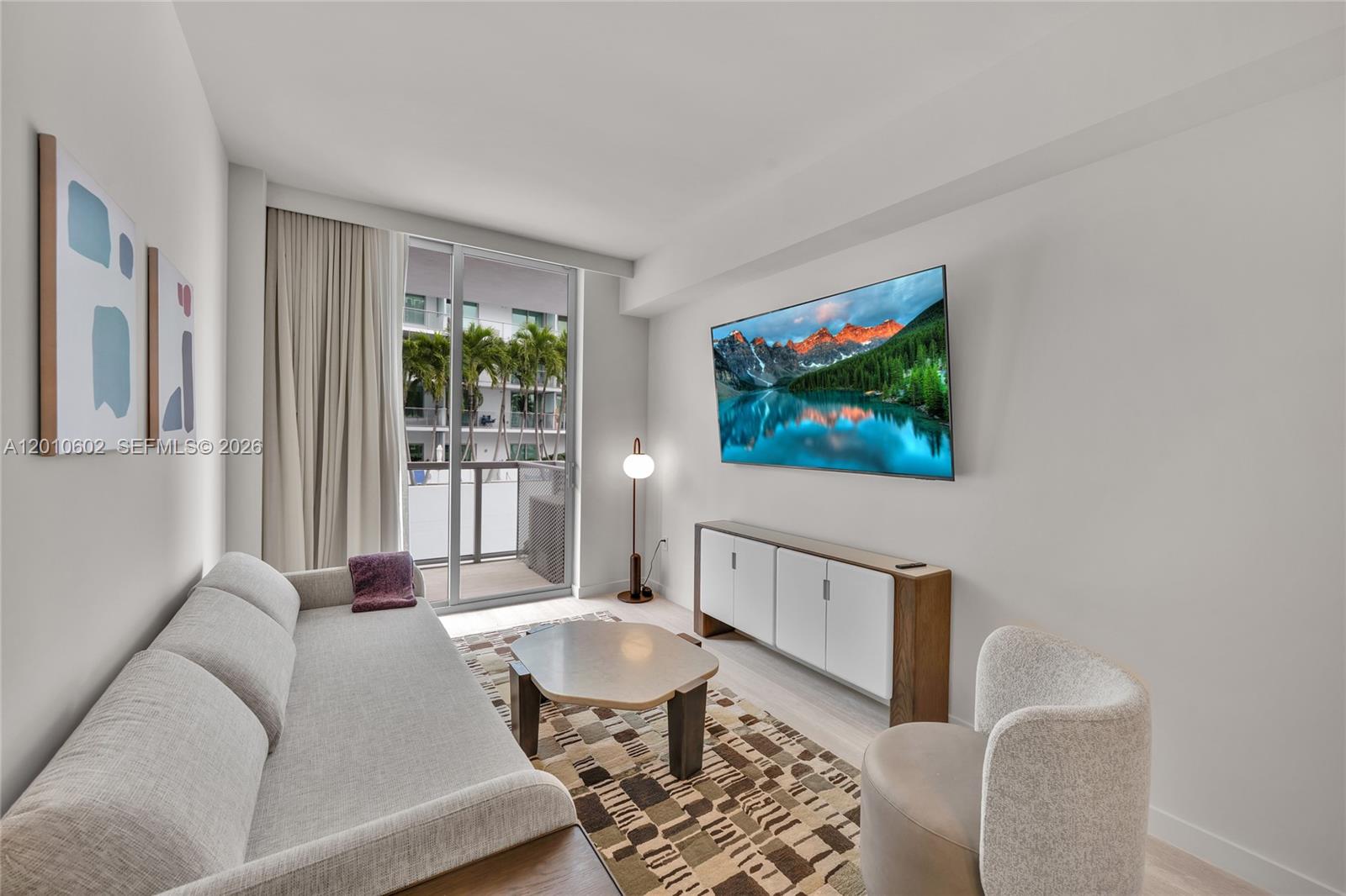 A modern living room features a sofa, coffee table, wall-mounted television, and a balcony view — 1611 SW 2nd Ave # 414, Miami FL 33129, MIAMI, FL