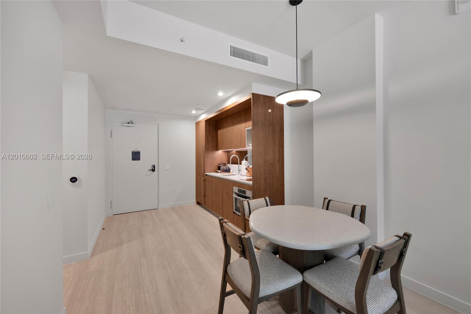 A dining area with a round table and kitchenette featuring wood cabinetry and light flooring — 1611 SW 2nd Ave # 414, Miami FL 33129, MIAMI, FL