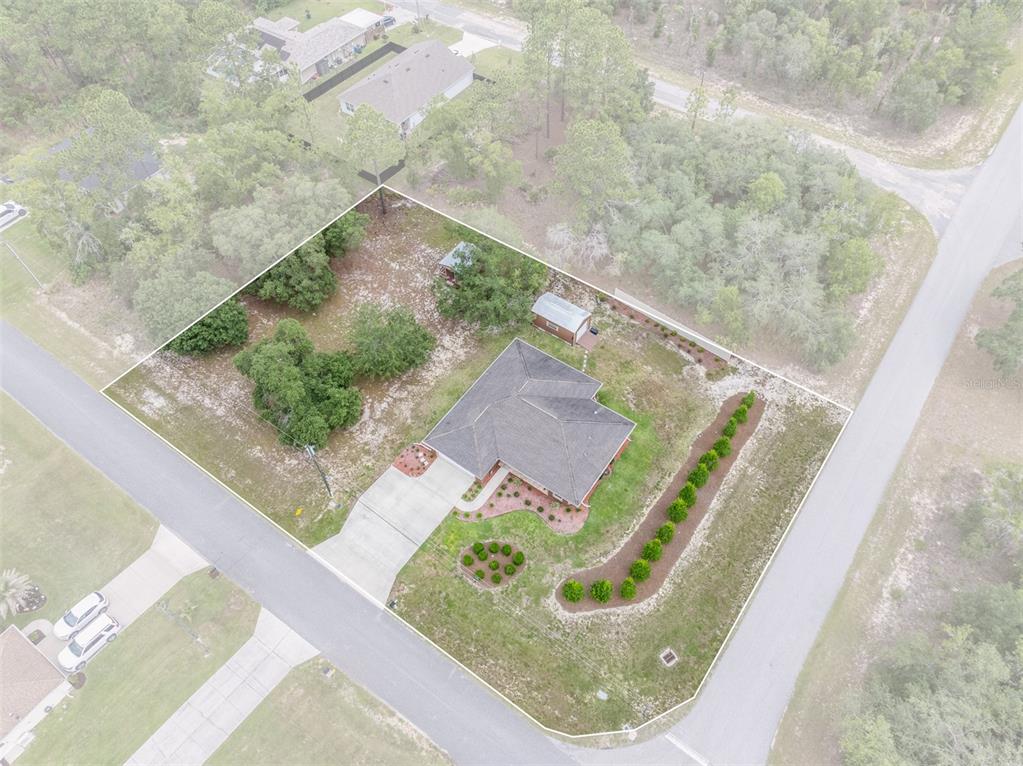 An aerial view shows a single-story house with a driveway and landscaping on a corner lot — 1763 W MCNEAL DRIVE, DUNNELLON, FL