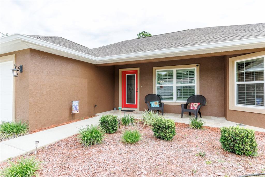 The exterior of a brown house features a red front door and a small porch — 1763 W MCNEAL DRIVE, DUNNELLON, FL