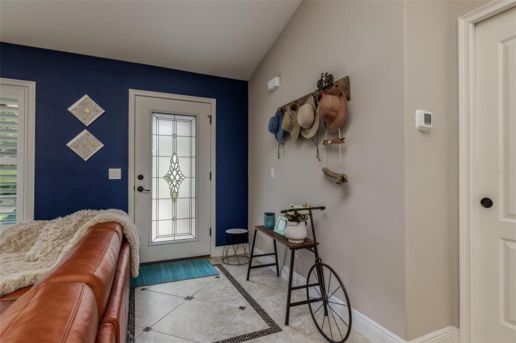 An entryway features a blue accent wall, a glass-paneled door, and a bicycle-themed console table — 1763 W MCNEAL DRIVE, DUNNELLON, FL