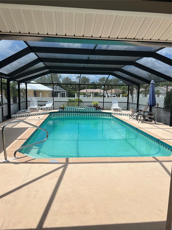 A screened-in swimming pool with a tiled border and a metal handrail on the deck — 3645 SLAYTON AVENUE, NORTH PORT, FL