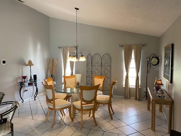 A dining room features a glass-topped table, six chairs, a chandelier, and tile flooring — 3645 SLAYTON AVENUE, NORTH PORT, FL