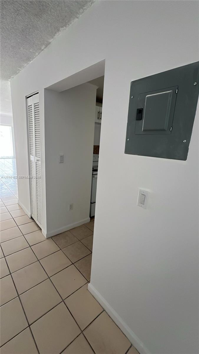 A hallway with tiled floors leads to a kitchen, featuring a wall-mounted electrical panel — 4480 Palm Ave # 402, Hialeah FL 33012, HIALEAH, FL