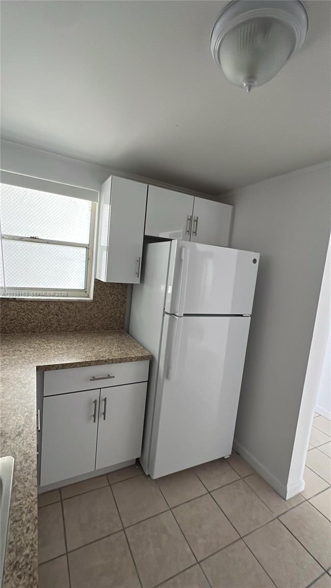 A kitchen features white cabinets, a white refrigerator, and speckled laminate countertops — 4480 Palm Ave # 402, Hialeah FL 33012, HIALEAH, FL