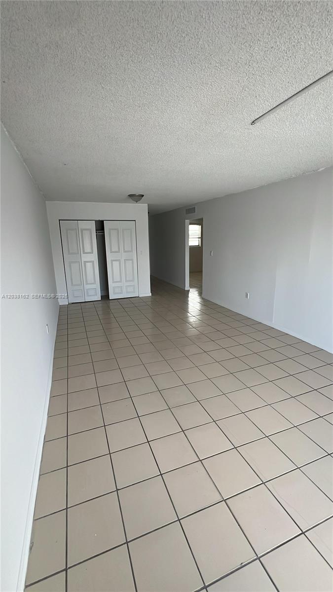An empty room features light-colored tile flooring, white walls, and a double-door closet — 4480 Palm Ave # 402, Hialeah FL 33012, HIALEAH, FL