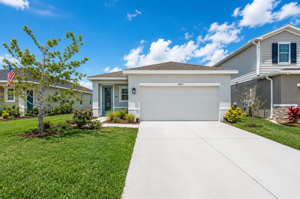 A single-story house with a white garage, light-colored stucco exterior, and a front lawn — 10616 HIGH NOON TRAIL, PARRISH, FL