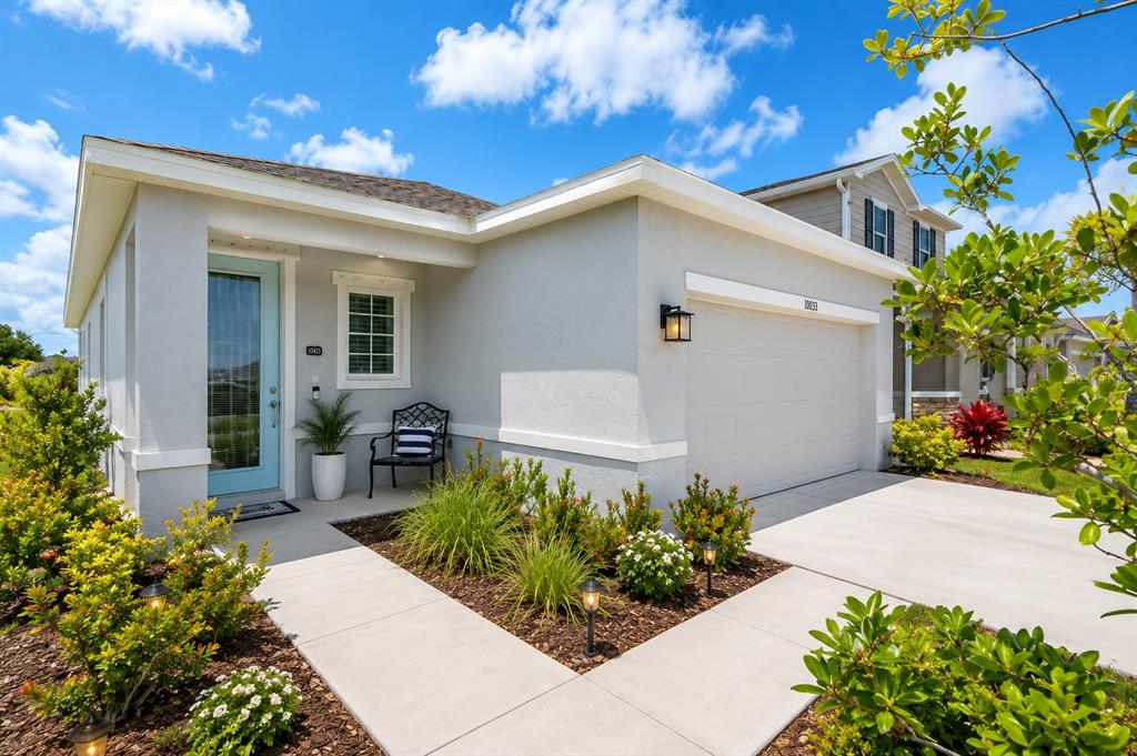 A light gray single-story house features a light blue front door and a two-car garage — 10616 HIGH NOON TRAIL, PARRISH, FL