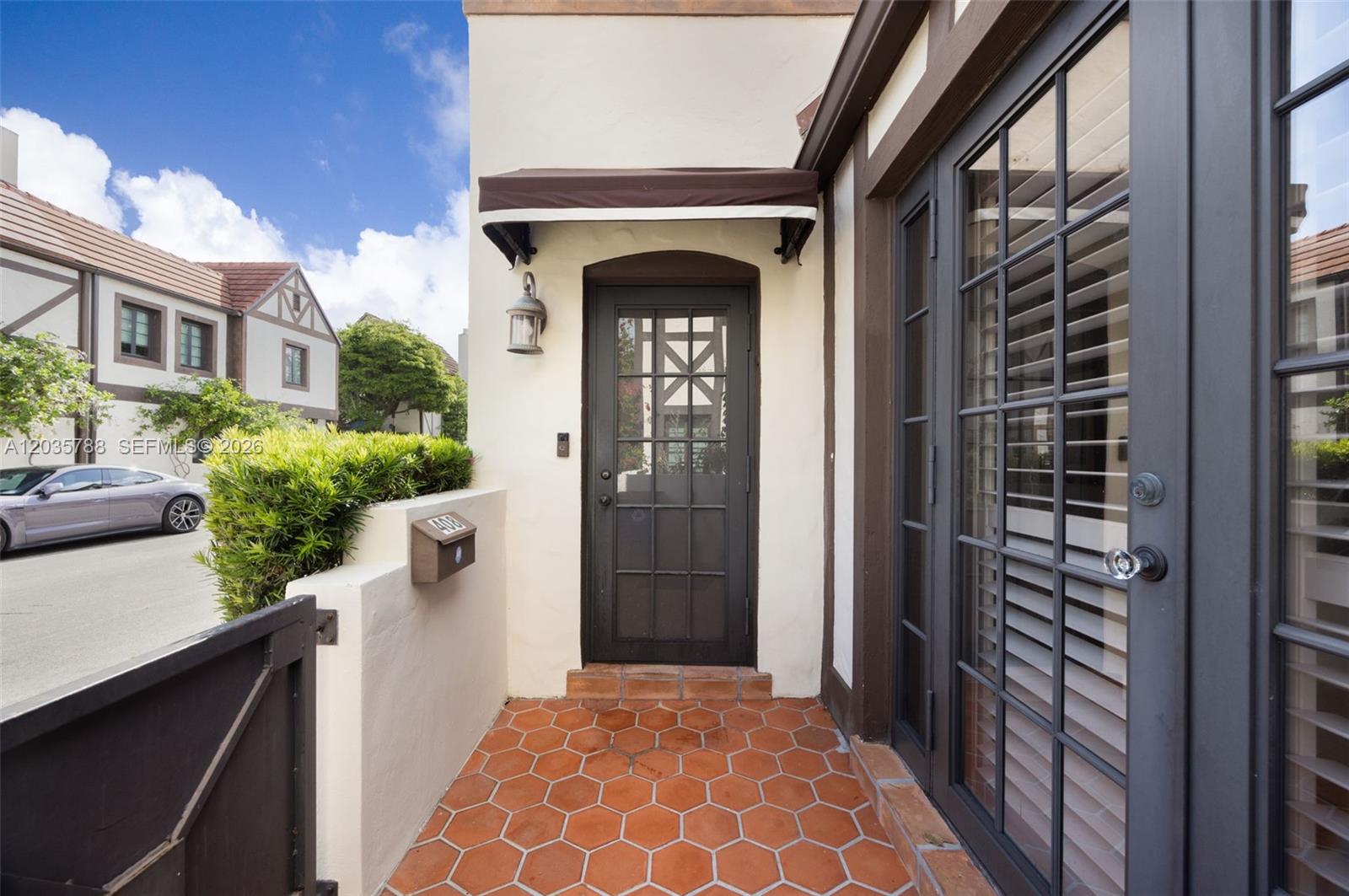 An exterior entryway features a dark-framed glass door, terracotta hexagonal floor tiles, and a mailbox — 408 Viscaya Ave, Coral Gables FL 33134, CORAL GABLES, FL