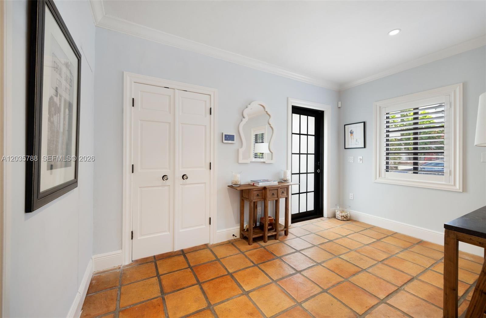 An entryway features terracotta tile flooring, a white double-door closet, and a black-framed glass door — 408 Viscaya Ave, Coral Gables FL 33134, CORAL GABLES, FL