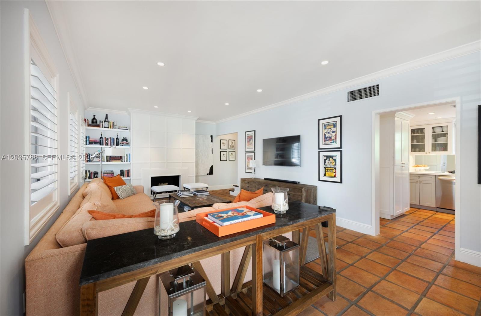 A living room features a fireplace, built-in shelving, a sofa, and terracotta tile flooring — 408 Viscaya Ave, Coral Gables FL 33134, CORAL GABLES, FL