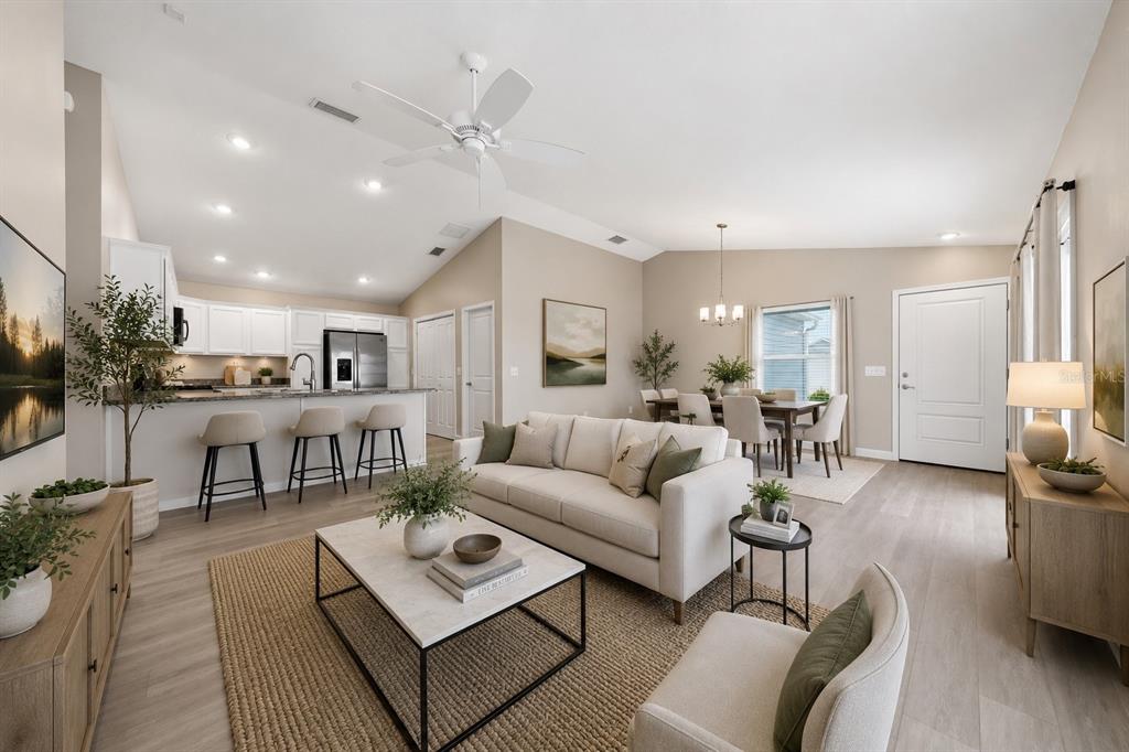 An open-concept living room and kitchen featuring a white sofa, dining area, and neutral decor — 302 ZINGALE LANE, THE VILLAGES, FL
