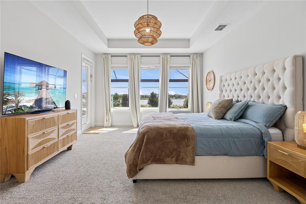 A bedroom features a tufted headboard, a wooden dresser, and a view of a lake — 9969 LOST CREEK DRIVE, WINTER GARDEN, FL