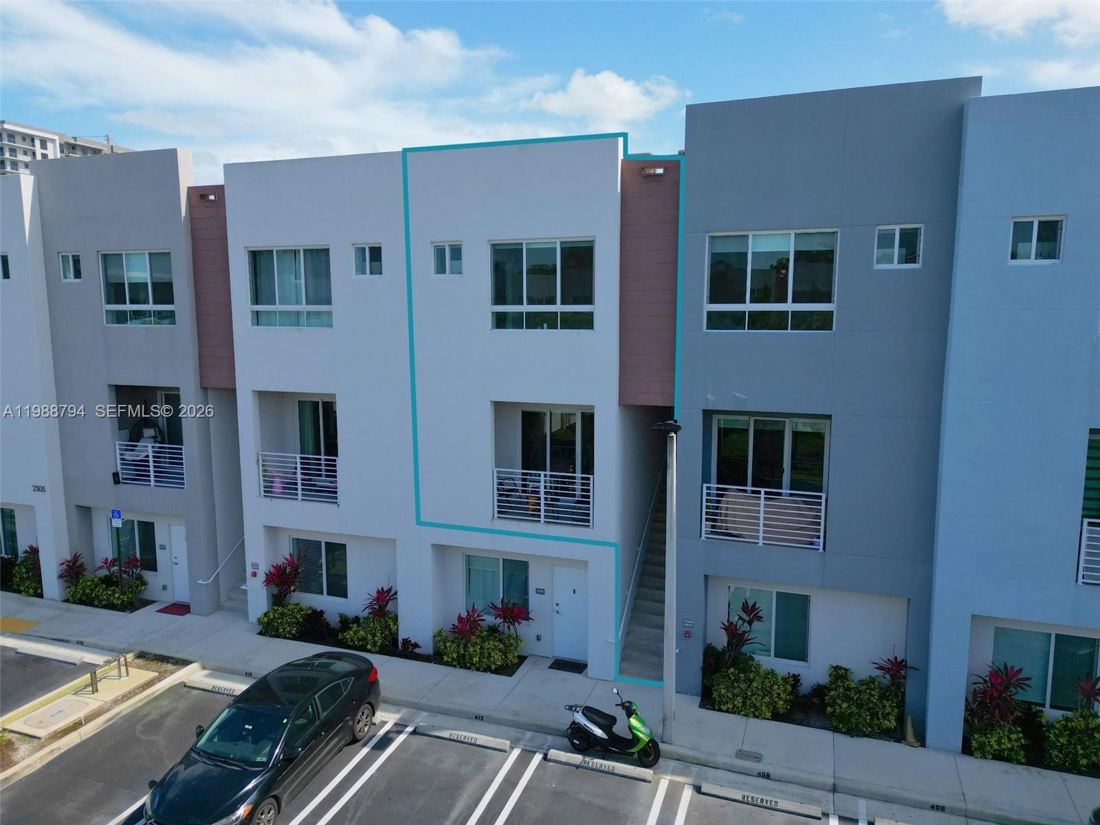 An exterior view of a modern three-story townhouse with a balcony and reserved parking — 2505 NE 193rd St # 4208, Miami FL 33180, MIAMI, FL