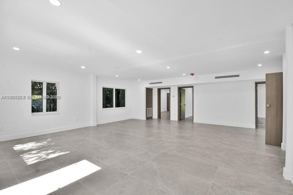 An empty, modern room features light gray tile flooring, white walls, and recessed ceiling lights — 7902 SW 67th Ave, South Miami FL 33143, SOUTH MIAMI, FL
