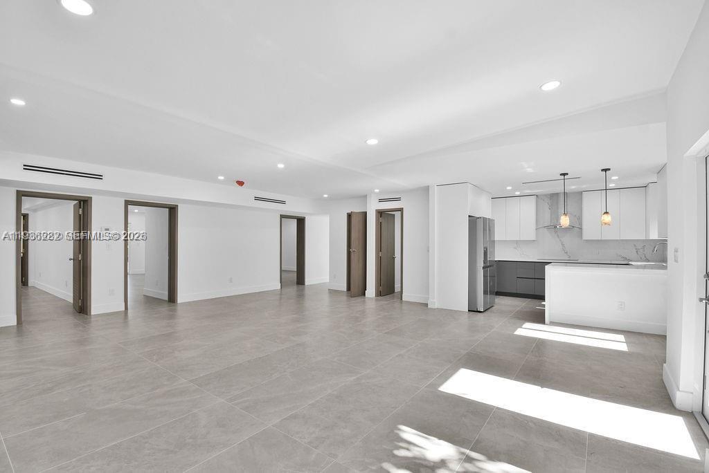 An open-concept living area features large gray floor tiles, white walls, and a modern kitchen — 7902 SW 67th Ave, South Miami FL 33143, SOUTH MIAMI, FL