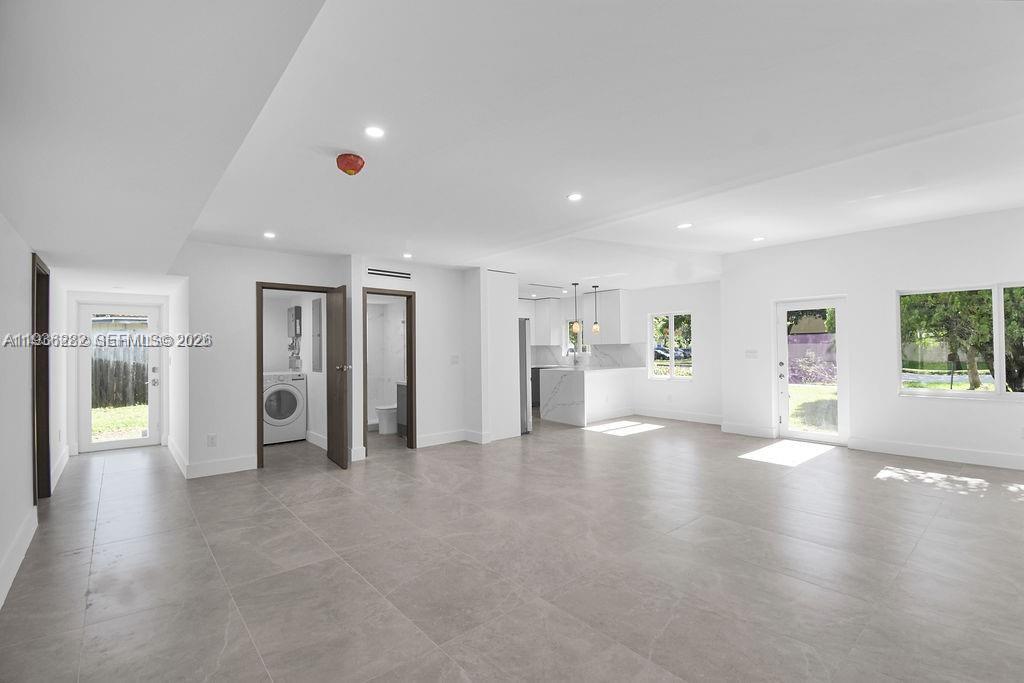 An open-concept living area features light gray tile flooring, white walls, and a kitchen — 7902 SW 67th Ave, South Miami FL 33143, SOUTH MIAMI, FL