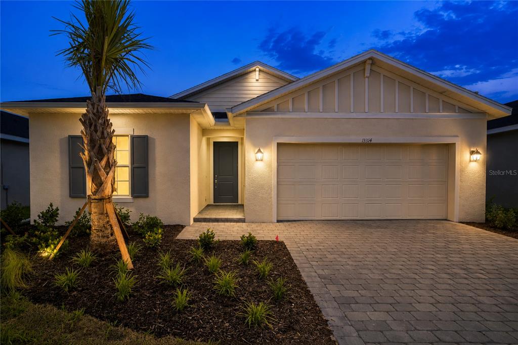 A single-story house with a paved driveway, two-car garage, and a palm tree at dusk — 13314 GRASSMERE COURT, PUNTA GORDA, FL