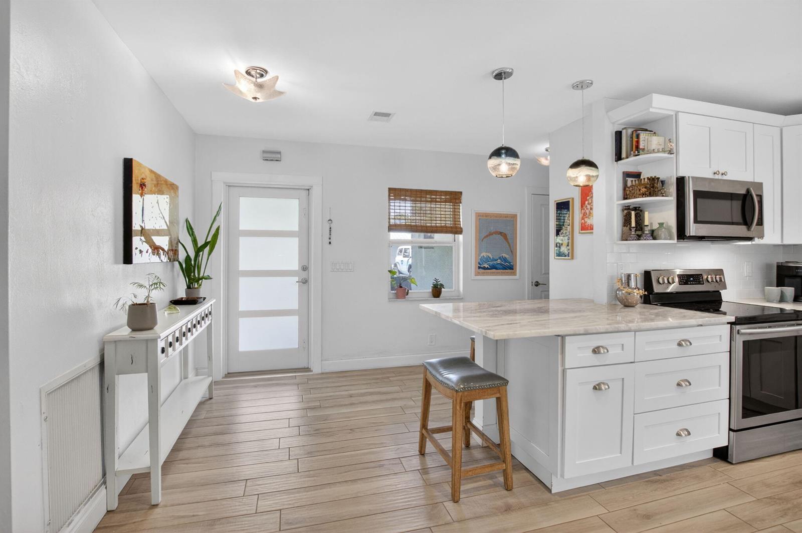 A patio features a white dining set with a blue umbrella on a paved surface — 1501 Dale Lane, Delray Beach FL 33444, DELRAY BEACH, FL