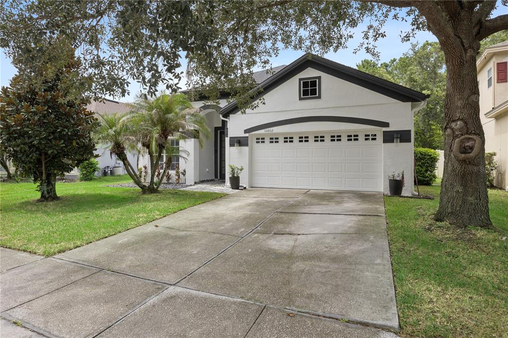 A single-story house with a white stucco facade, dark trim, and a two-car garage — 10802 ARBOR VIEW BOULEVARD, ORLANDO, FL