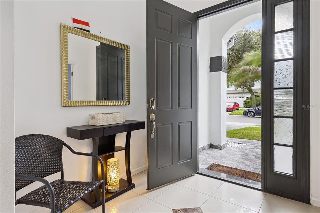 An entryway features a dark door, a wicker chair, a console table, and a wall mirror — 10802 ARBOR VIEW BOULEVARD, ORLANDO, FL