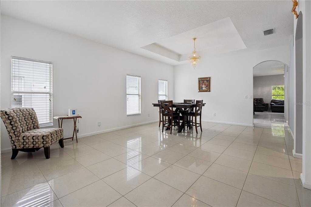 A dining room with white walls, tile flooring, a chandelier, and a patterned armchair — 10802 ARBOR VIEW BOULEVARD, ORLANDO, FL