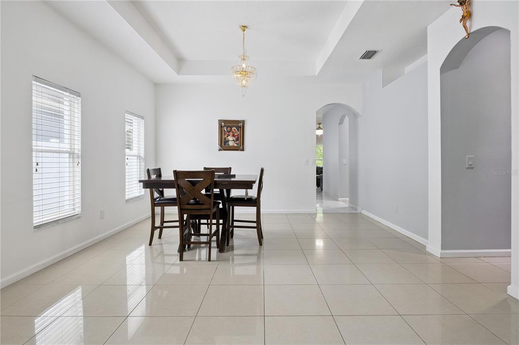 A dining room features a tray ceiling, chandelier, tile flooring, and a dark wood table — 10802 ARBOR VIEW BOULEVARD, ORLANDO, FL