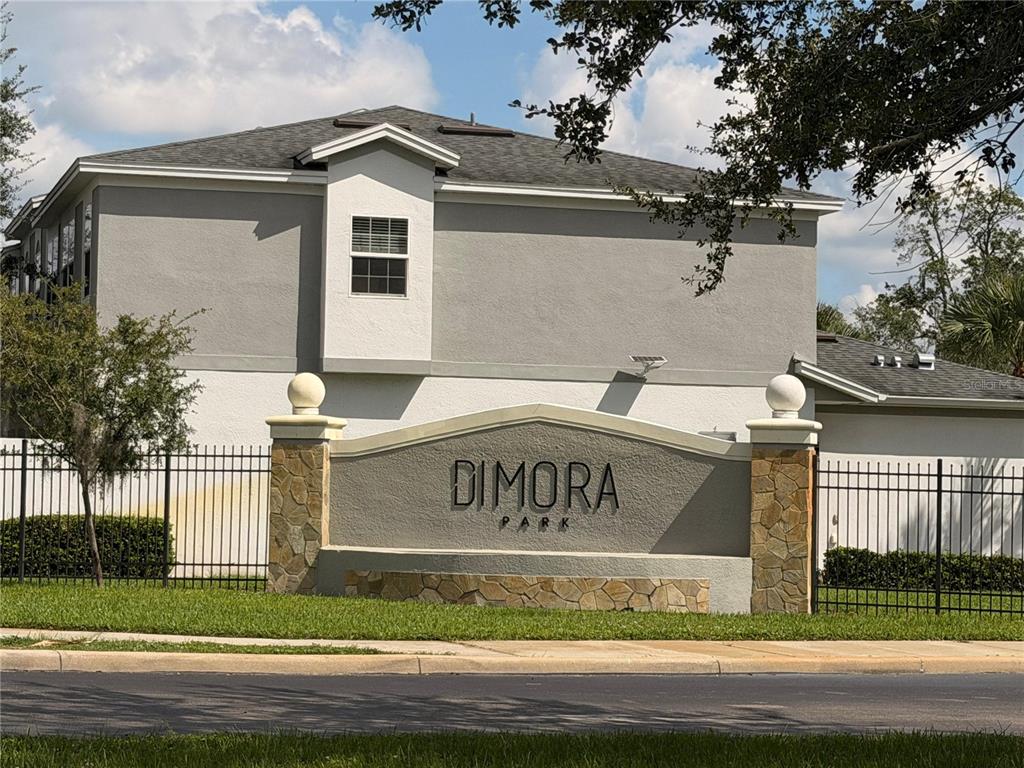 A stone and stucco monument sign for Dimora Park stands before a two-story residential building — 2124 PENNY LANE, KISSIMMEE, FL