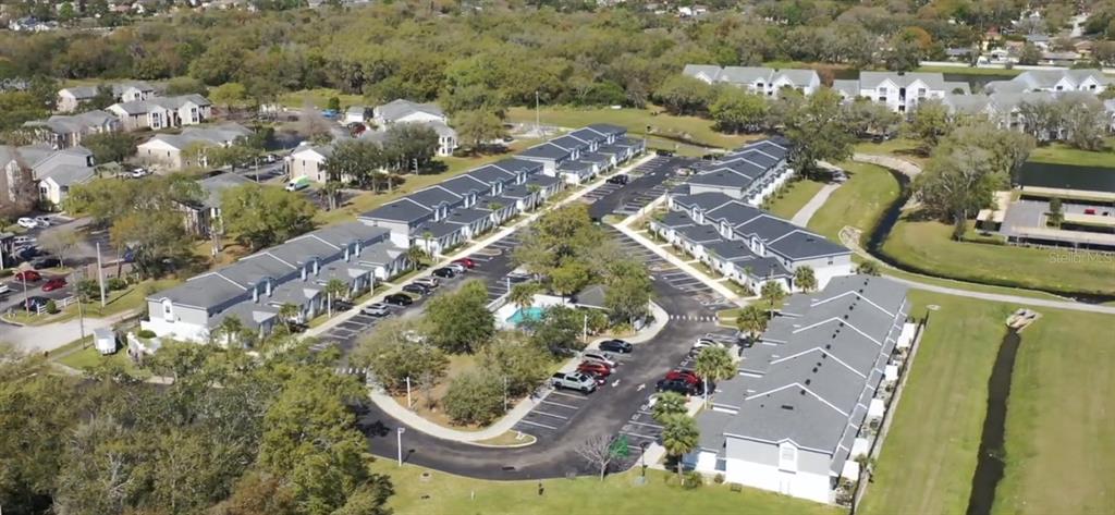 An aerial view shows multiple multi-story residential buildings with gray roofs and surrounding parking lots — 2124 PENNY LANE, KISSIMMEE, FL