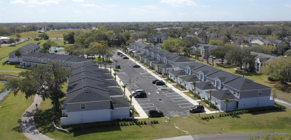 An aerial view shows multiple rows of townhomes with dark roofs and parking lots — 2124 PENNY LANE, KISSIMMEE, FL