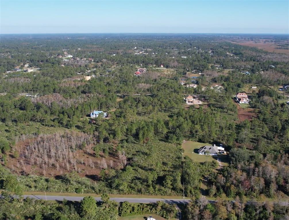 An aerial view shows a rural landscape with scattered houses, dense trees, and a paved road — Lot 640 SHELDON STREET, ORLANDO, FL