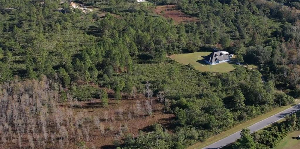 An aerial view shows a house surrounded by dense forest and a paved road — Lot 640 SHELDON STREET, ORLANDO, FL
