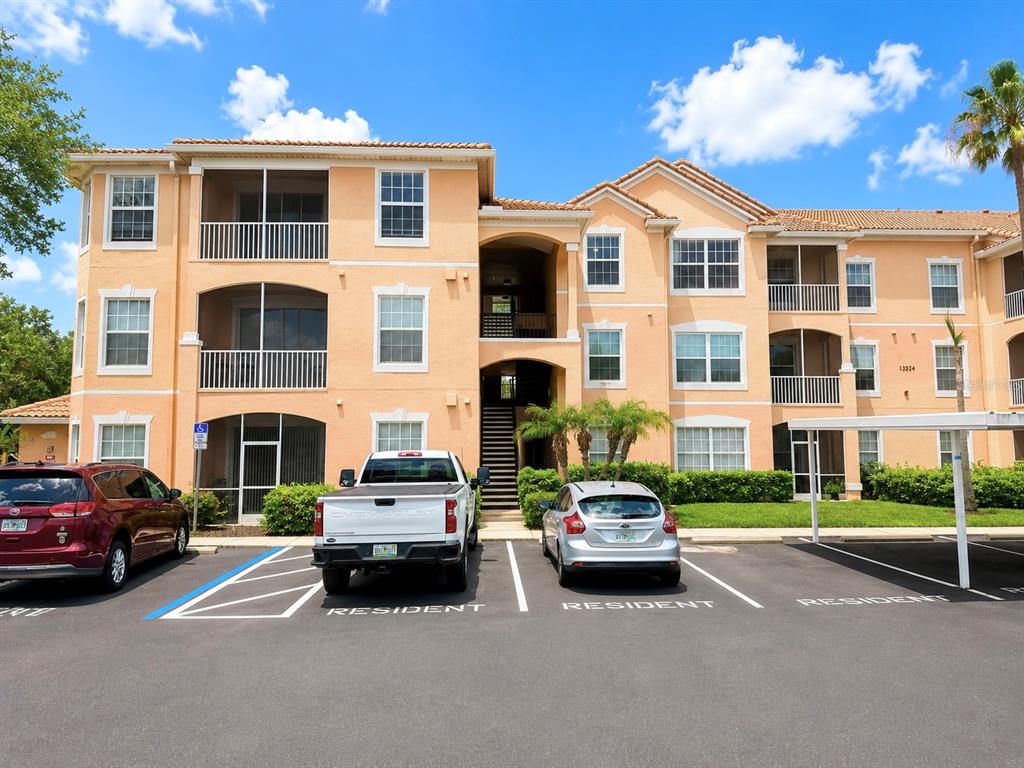 A three-story apartment building with tan stucco walls and a parking lot in front — 13524 TURTLE MARSH LOOP UNIT 634, ORLANDO, FL