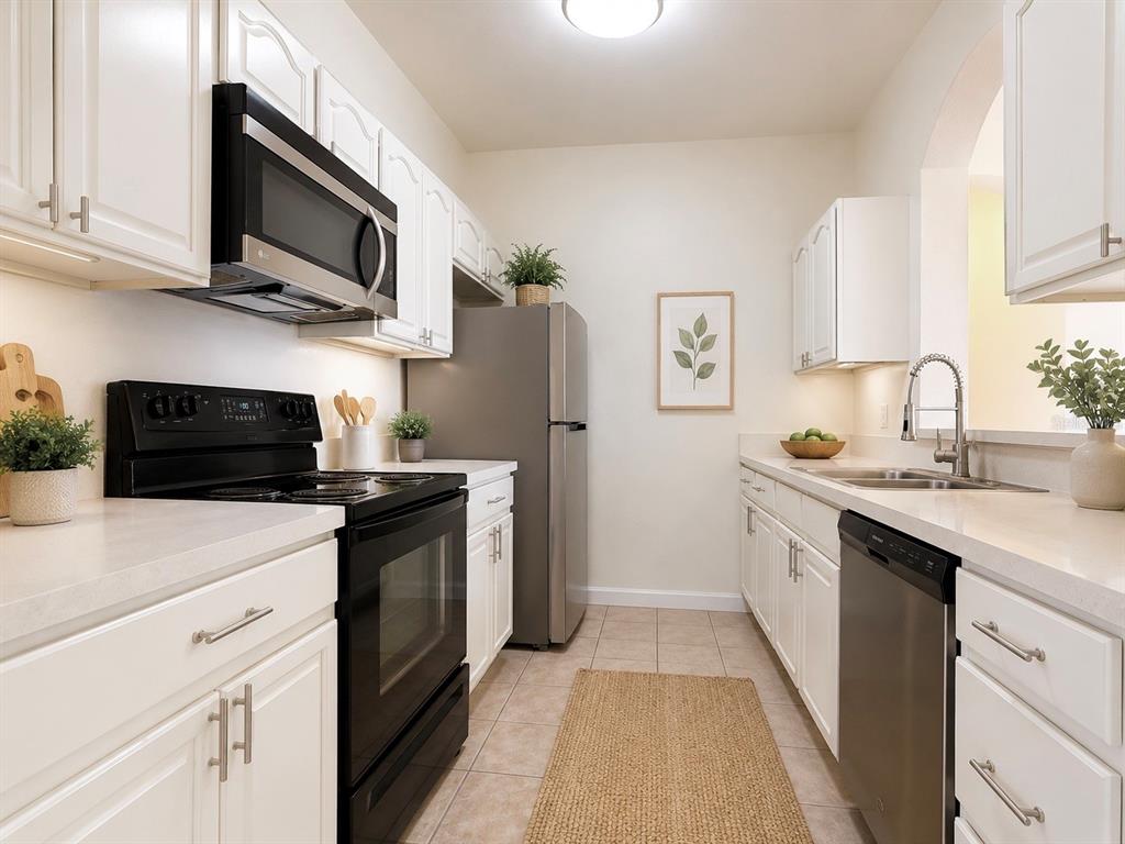 A galley kitchen features white cabinets, stainless steel appliances, and light-colored countertops — 13524 TURTLE MARSH LOOP UNIT 634, ORLANDO, FL