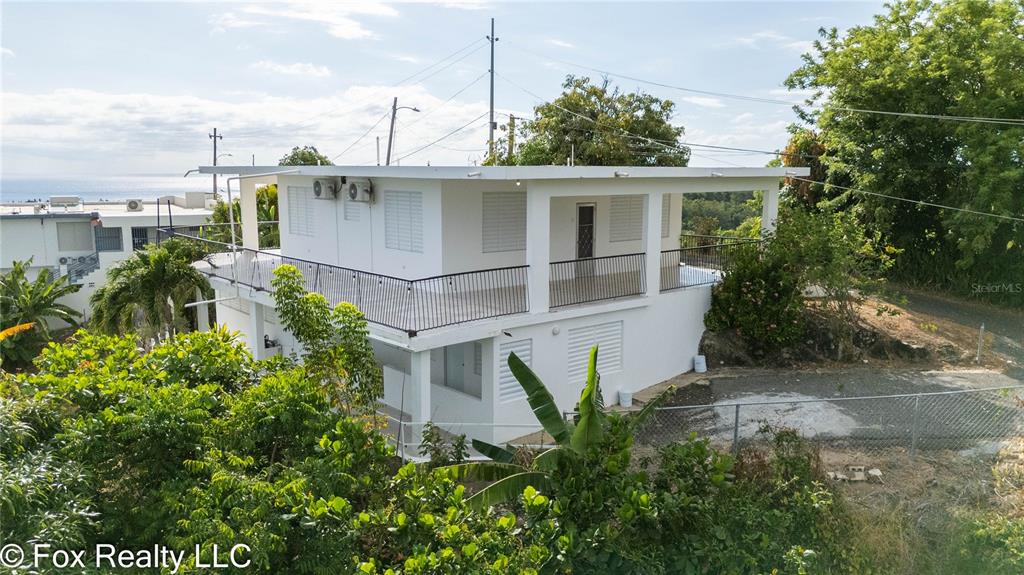 A balcony with a white railing overlooks a lush green forest and the ocean — 412 INT CARR BO PUEBLO, RINCON, PR