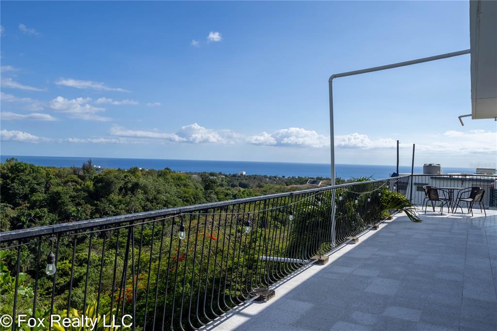 An elevated exterior view shows white houses nestled among lush green trees overlooking the ocean — 412 INT CARR BO PUEBLO, RINCON, PR