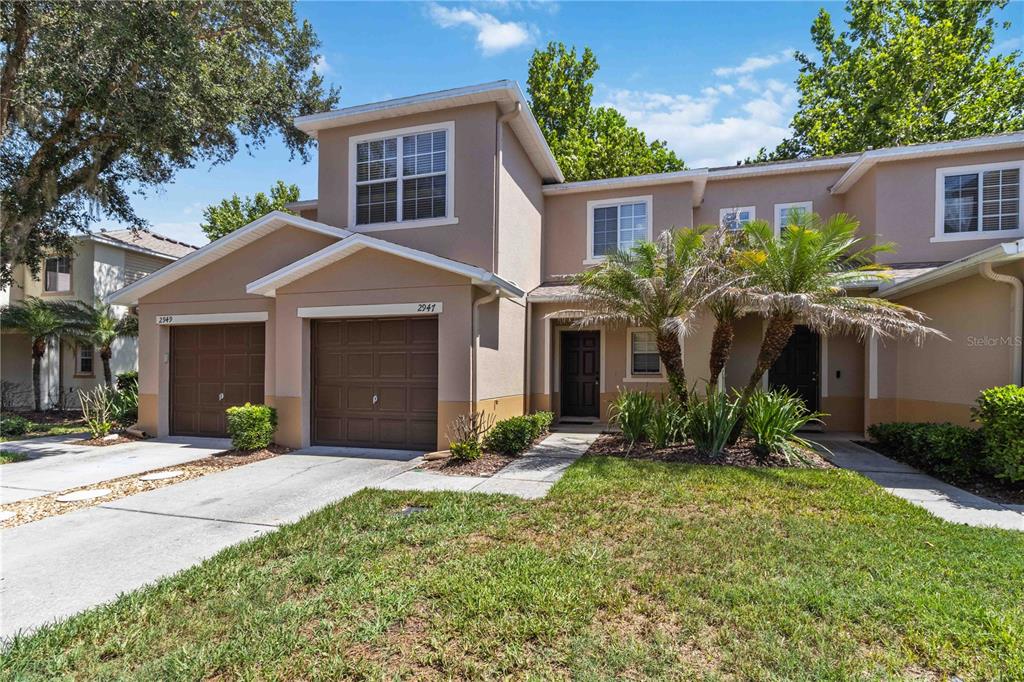 A two-story townhouse with a tan stucco exterior, two garage doors, and a front lawn — 2947 ROYAL TUSCAN LANE, VALRICO, FL
