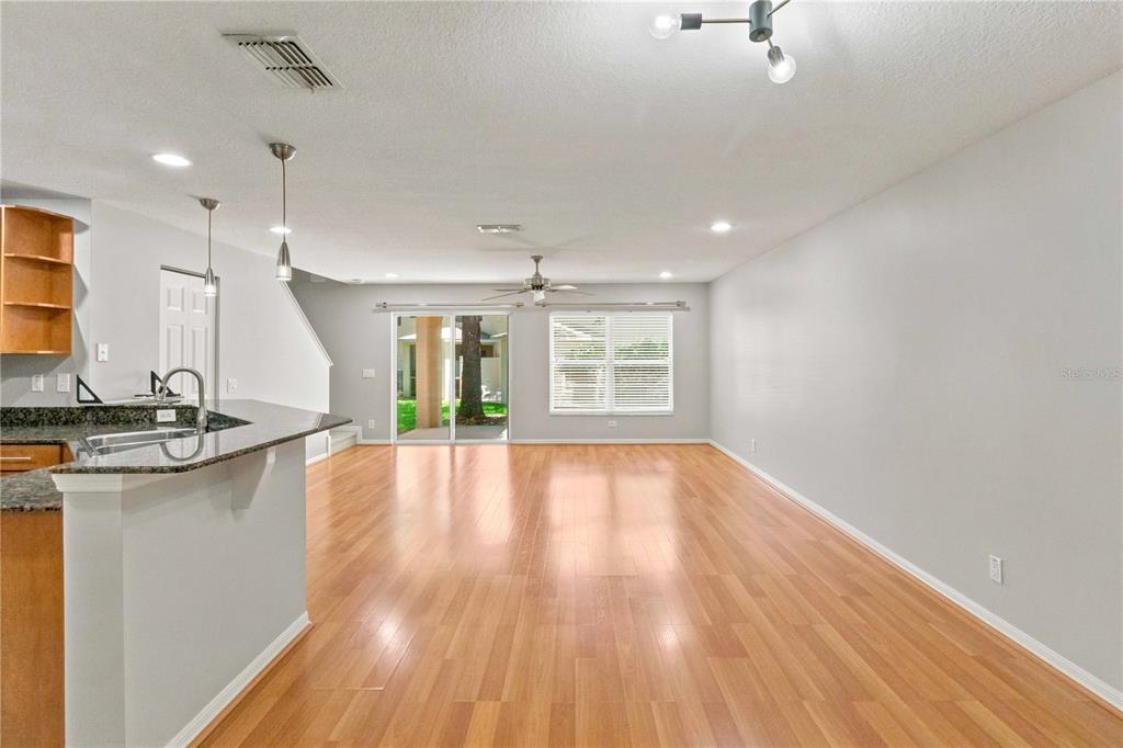 An open-concept living area features wood-look flooring, a kitchen island, and sliding glass doors — 2947 ROYAL TUSCAN LANE, VALRICO, FL