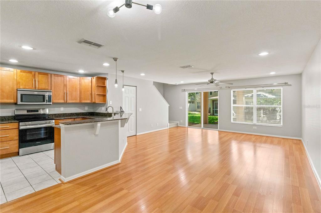 An open-concept kitchen and living area with wood flooring, light cabinetry, and a sliding door — 2947 ROYAL TUSCAN LANE, VALRICO, FL