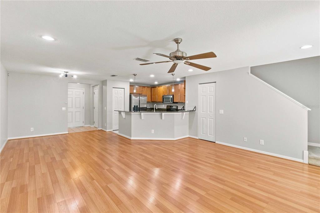 An open-concept living area features light wood flooring, a kitchen island, and a ceiling fan — 2947 ROYAL TUSCAN LANE, VALRICO, FL