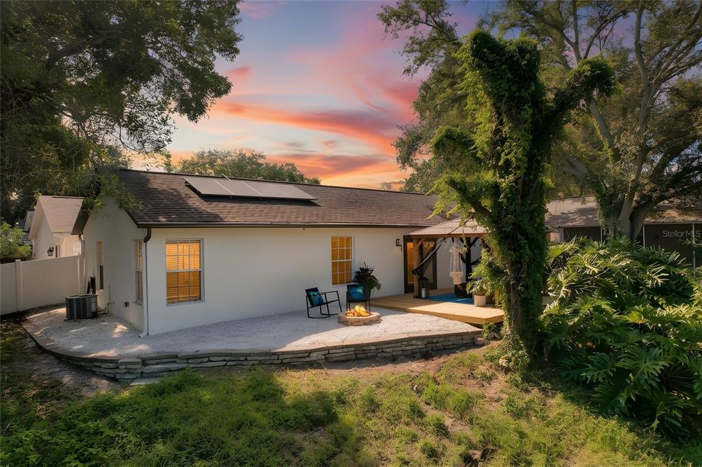 The exterior of a white house features a gravel patio, fire pit, and wooden deck — 2751 WILSON COURT, PALM HARBOR, FL