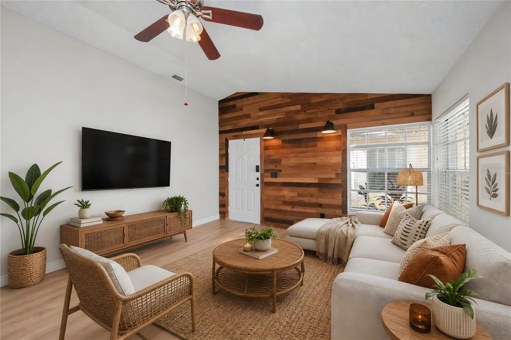 A living room features a wood-paneled accent wall, a sectional sofa, and a television — 2751 WILSON COURT, PALM HARBOR, FL