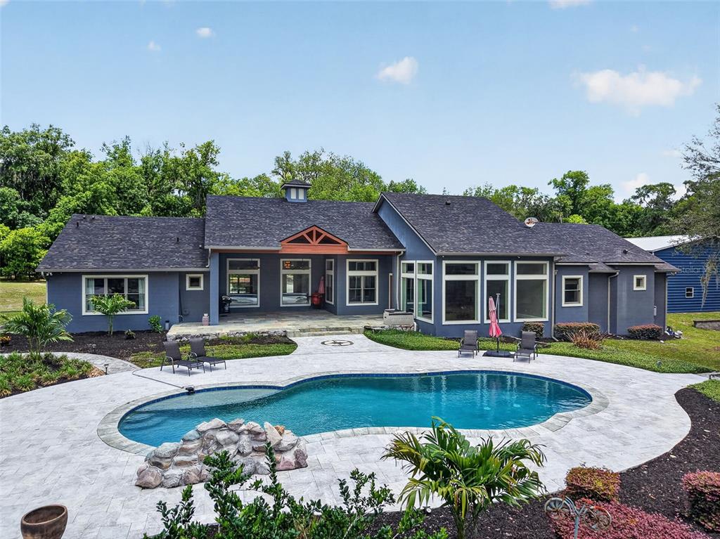 An aerial view shows a house with a pool, patio, and detached garage in woods — 2110 HIGHLAND PARK ROAD, DELAND, FL