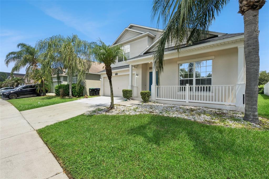 A two-story suburban house with a white porch, a concrete driveway, and several palm trees — 2029 GREAT FALLS WAY, ORLANDO, FL