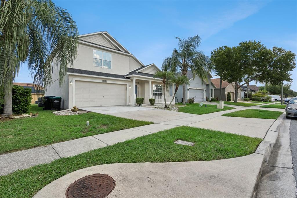 A two-story suburban house with a beige exterior, a two-car garage, and a palm tree — 2029 GREAT FALLS WAY, ORLANDO, FL