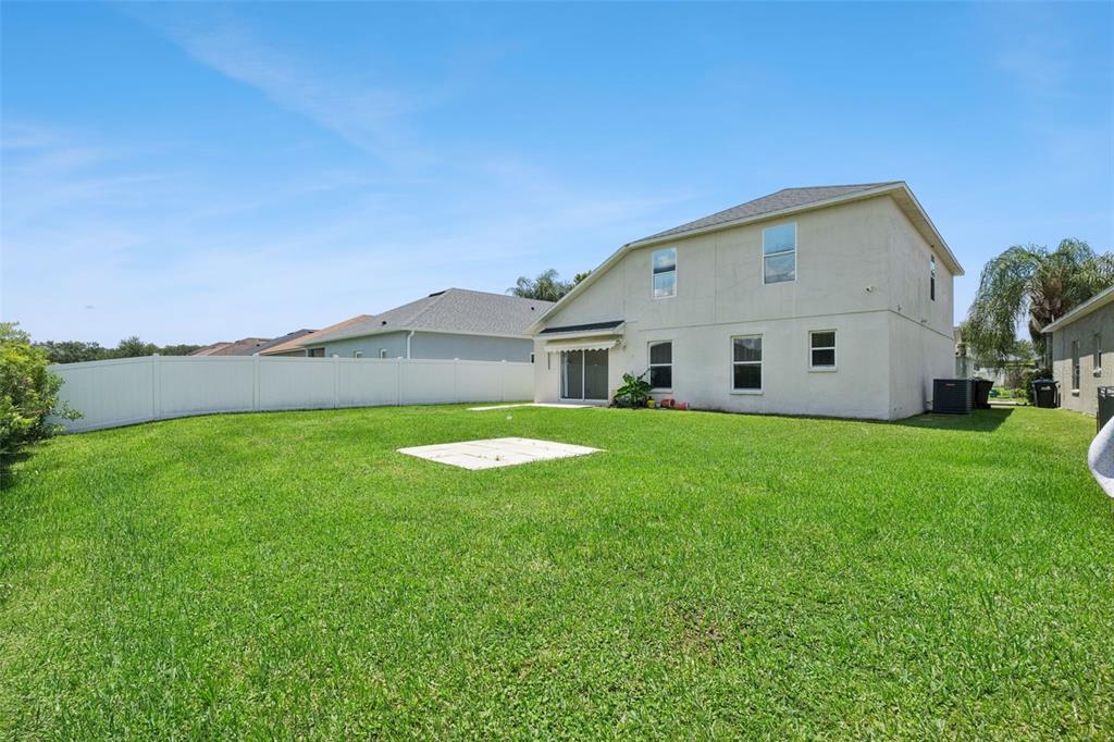 The backyard of a two-story house features a large lawn and a white vinyl fence — 2029 GREAT FALLS WAY, ORLANDO, FL